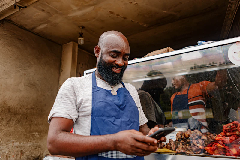 Small business owner in an apron checking orders on a phone