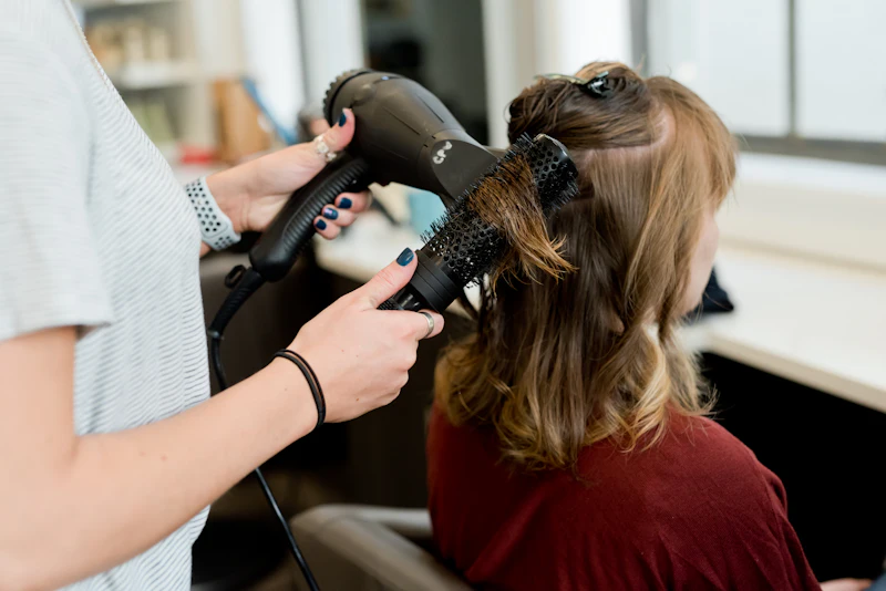 Hairstylist blow-drying a client's hair in a salon